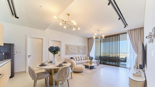 Uma sala de estar moderna com área de jantar, um sofá, uma mesa de centro e vista para o exterior.