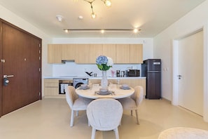 Een moderne keuken met houten kastjes, een eettafel met vier stoelen en een koelkast.