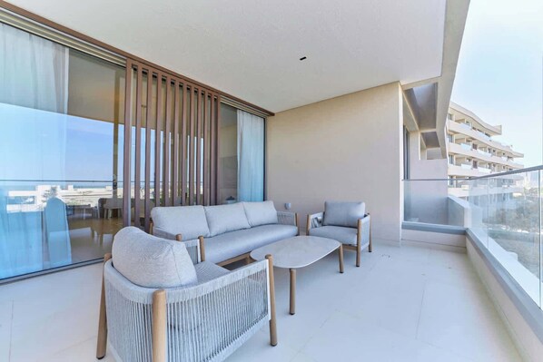 A balcony with a sofa, two armchairs, and a coffee table.