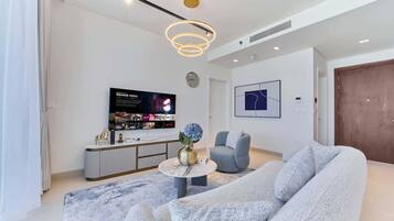 Un salon moderne doté d’un grand téléviseur à écran plat, d’une table basse ronde, d’un canapé gris et d’un style de décoration minimaliste.