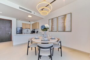 Une cuisine moderne dotée d’un îlot central, d’un coin repas avec une table ronde et des chaises, et d’un vase décoratif orné de fleurs.