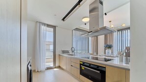 Una cocina moderna con horno empotrado, lavavajillas y un amplio ventanal con cortinas.