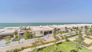 Un hotel costero con varias edificaciones, un estacionamiento y vistas al mar.