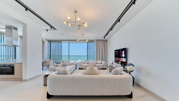 Una habitación de hotel moderna con una cama grande, televisión y vista al océano.
