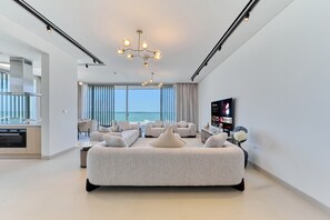 Een moderne hotelkamer met een groot bed, een televisie en uitzicht op de oceaan.