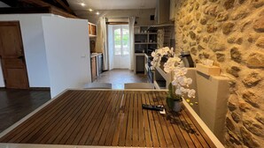 A modern kitchen with stone walls, wooden flooring, and a view into the dining area. - Papillon - Large 90m² apartment in the magnificent village of Seillans (Seillans)