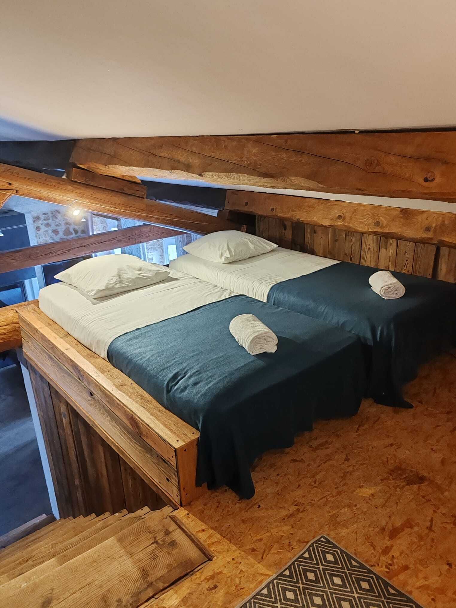 Una cama litera de madera con dos almohadas y dos toallas enrolladas.
