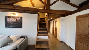 A narrow hallway with a wooden staircase leading to a door. A bed with pillows is visible on the left. - Papillon - Large 90m² apartment in the magnificent village of Seillans (Seillans)