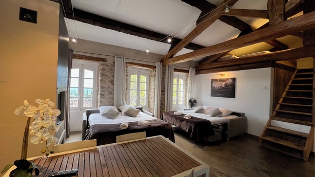 A rustic room with two beds, a wooden table, and a staircase. - Papillon - Large 90m² apartment in the magnificent village of Seillans (Seillans)