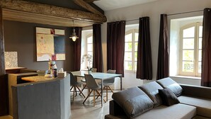 A modern living room with a sofa, dining table, and chairs. There is a painting on the wall and a potted plant on the table. - Papillon - Large 90m² apartment in the magnificent village of Seillans (Seillans)