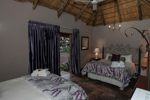 A bedroom with two beds, a thatched roof, and a view of the outdoors. - SUN DOWN LODGE & CONFERENCE (Maletswai)