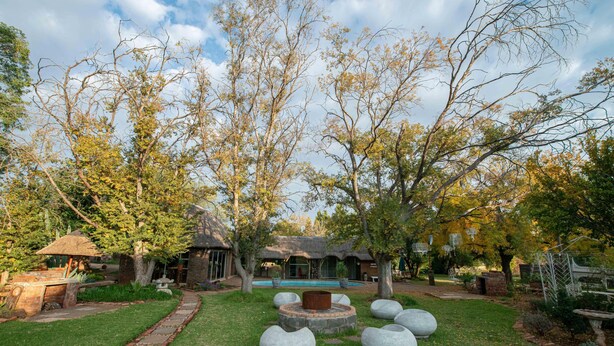 A garden with a stone fire pit, seating areas, and a pool. - SUN DOWN LODGE & CONFERENCE (Maletswai)