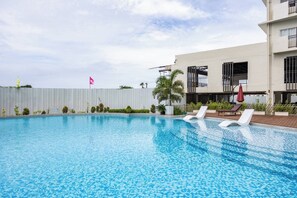 Ein Swimmingpool mit Liegestühlen und einem Gebäude im Hintergrund.