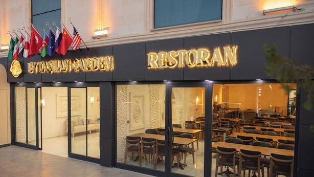 Ein Restaurant mit Glasfassade, mehreren Flaggen und einem Schild mit der Aufschrift 'BYTESHAW GARDEN RESTORAN'.