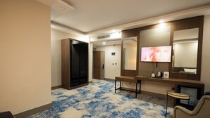 Ein Hotelzimmer mit einem großen Spiegel, einem Fernseher, einem Schreibtisch und einem Stuhl.