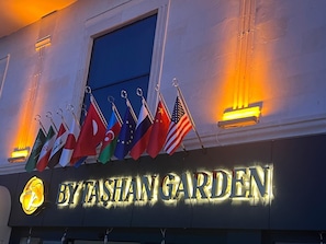 Un letrero de hotel con varias banderas y un cartel iluminado.