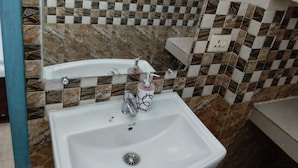 Ein Badezimmer mit einem weißen Waschbecken, einem Spiegel und Wandfliesen mit Muster.