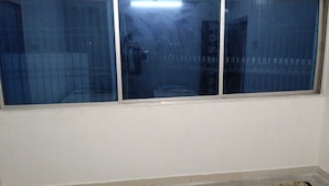 Ein Zimmer mit einem großen Fenster, einer weißen Wand und dem Spiegelbild einer Person.