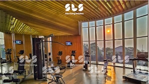 Un gimnasio amplio con diverso equipo de ejercicio, ventanas grandes y techo de madera.
