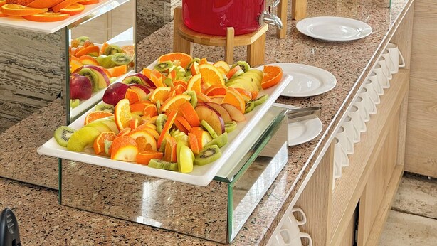Een buffet met diverse soorten fruit, sappen en gebak.