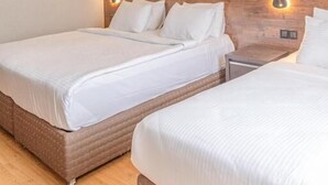 Een hotelkamer met twee bedden, een houten hoofdeinde en wandlampen.
