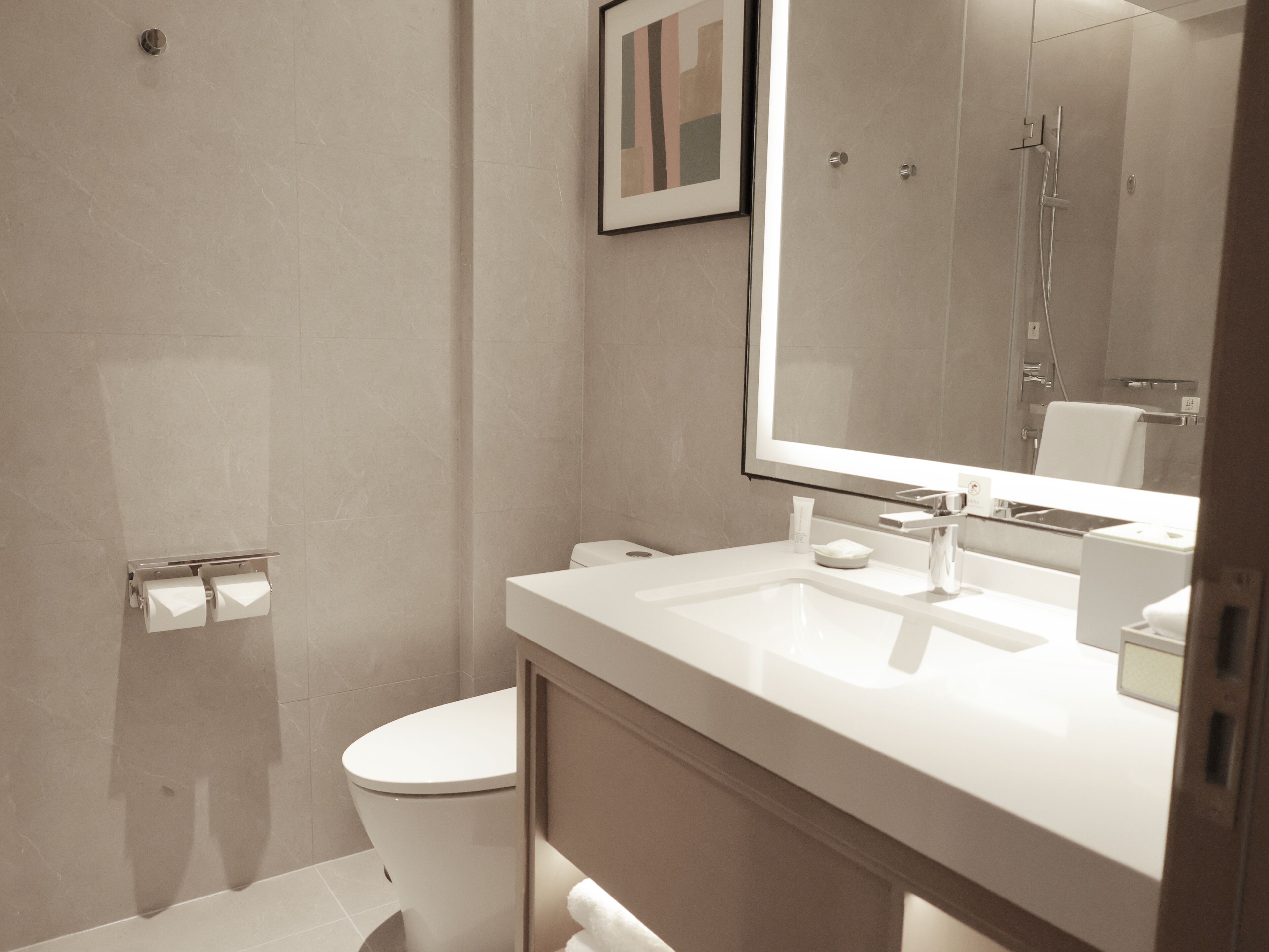 Ein modernes Badezimmer mit Toilette, Waschbecken, Spiegel und Dusche.