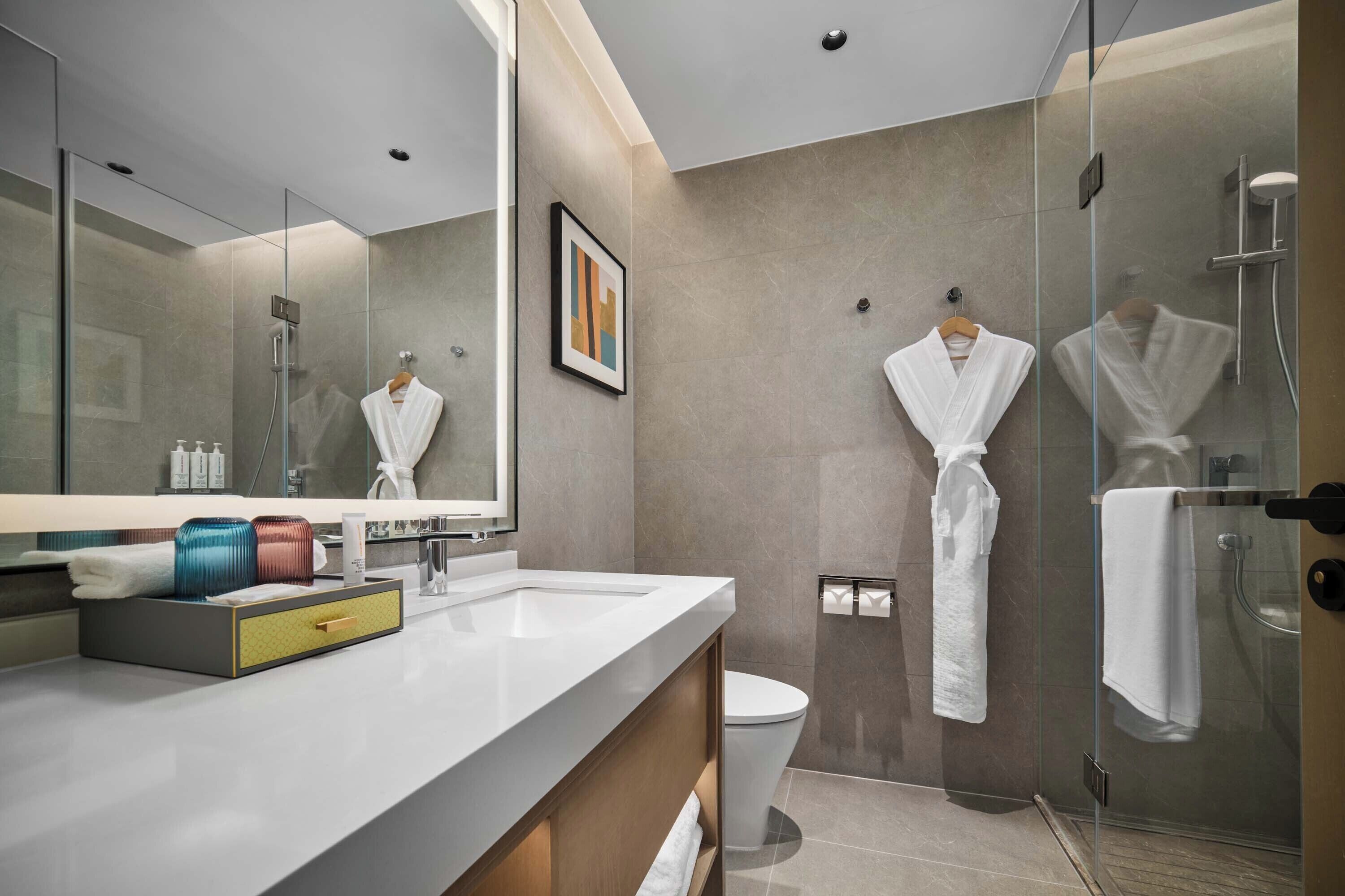 A modern bathroom with a glass shower enclosure, a white sink, and a toilet.