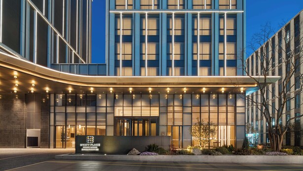Un hotel modern amb façana corba, grans finestres i entrada ben il·luminada.