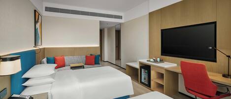 A hotel room with two beds, a desk, a chair, a TV, and a minibar.