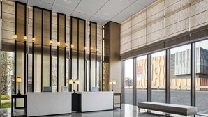 Una zona d'entrada moderna amb taulell de recepció, seients i grans finestres.