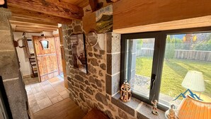 Un interior rústico con paredes de piedra, vigas de madera y vistas a un patio trasero.