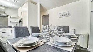 A dining area with a long table set for four, equipped with plates, glasses, and cutlery.