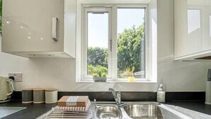 A modern kitchen with a large window, stainless steel sink, and a countertop with kitchen appliances.