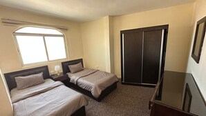 Ein Schlafzimmer mit zwei Betten, einem Kleiderschrank und einem Fernseher.