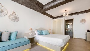 Ein Schlafzimmer mit Bett, Nachttischen, einer Couch, einer Kristallleuchtre und einem Spiegel.