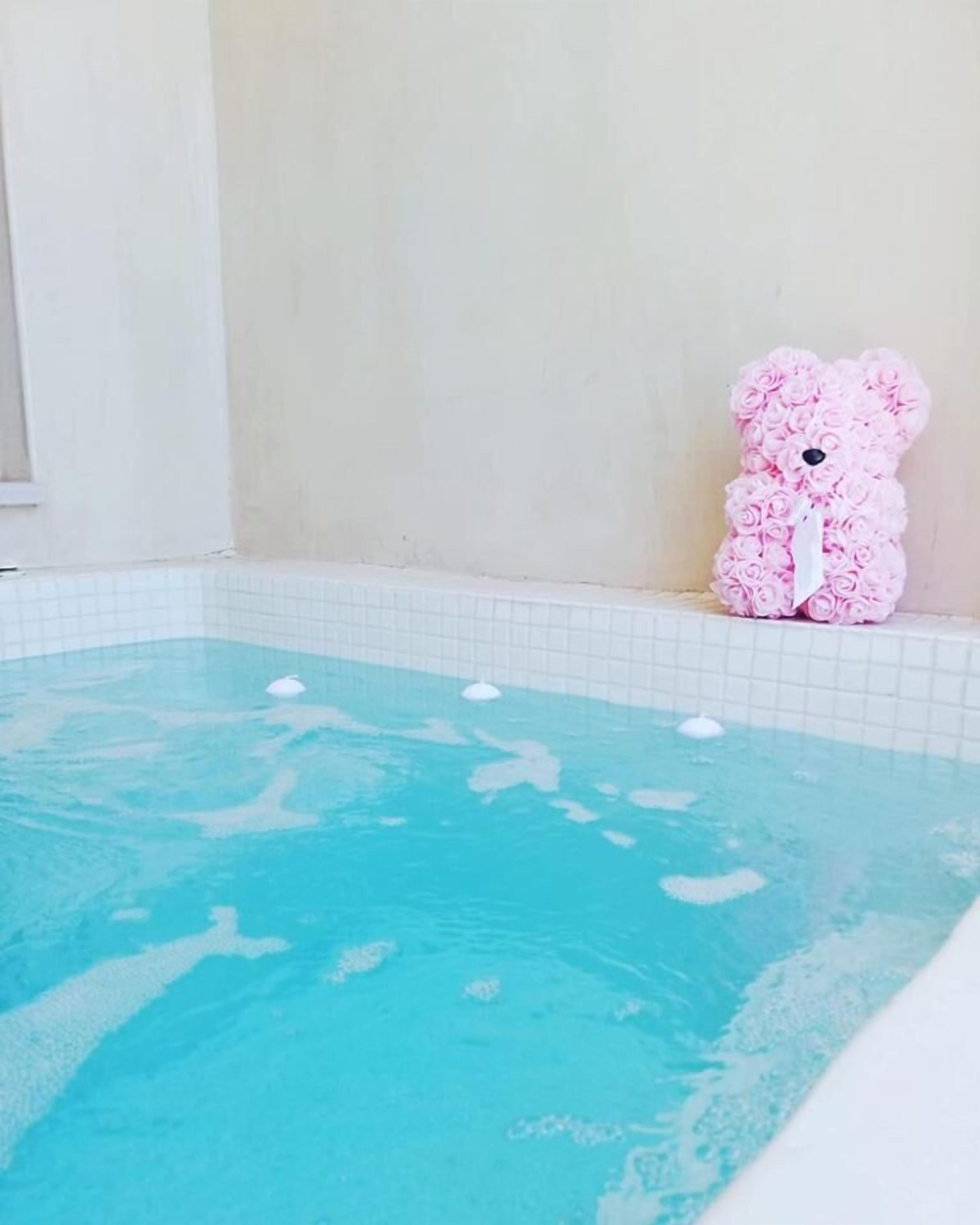 Ein kleiner, rechteckiger Pool mit klarem, blauem Wasser und einer rosafarbenen, bärenförmigen Dekoration aus Rosen.