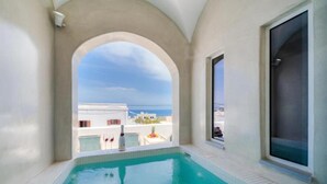 Ein Schwimmbecken mit Blick auf das Meer und Gebäude im Hintergrund.