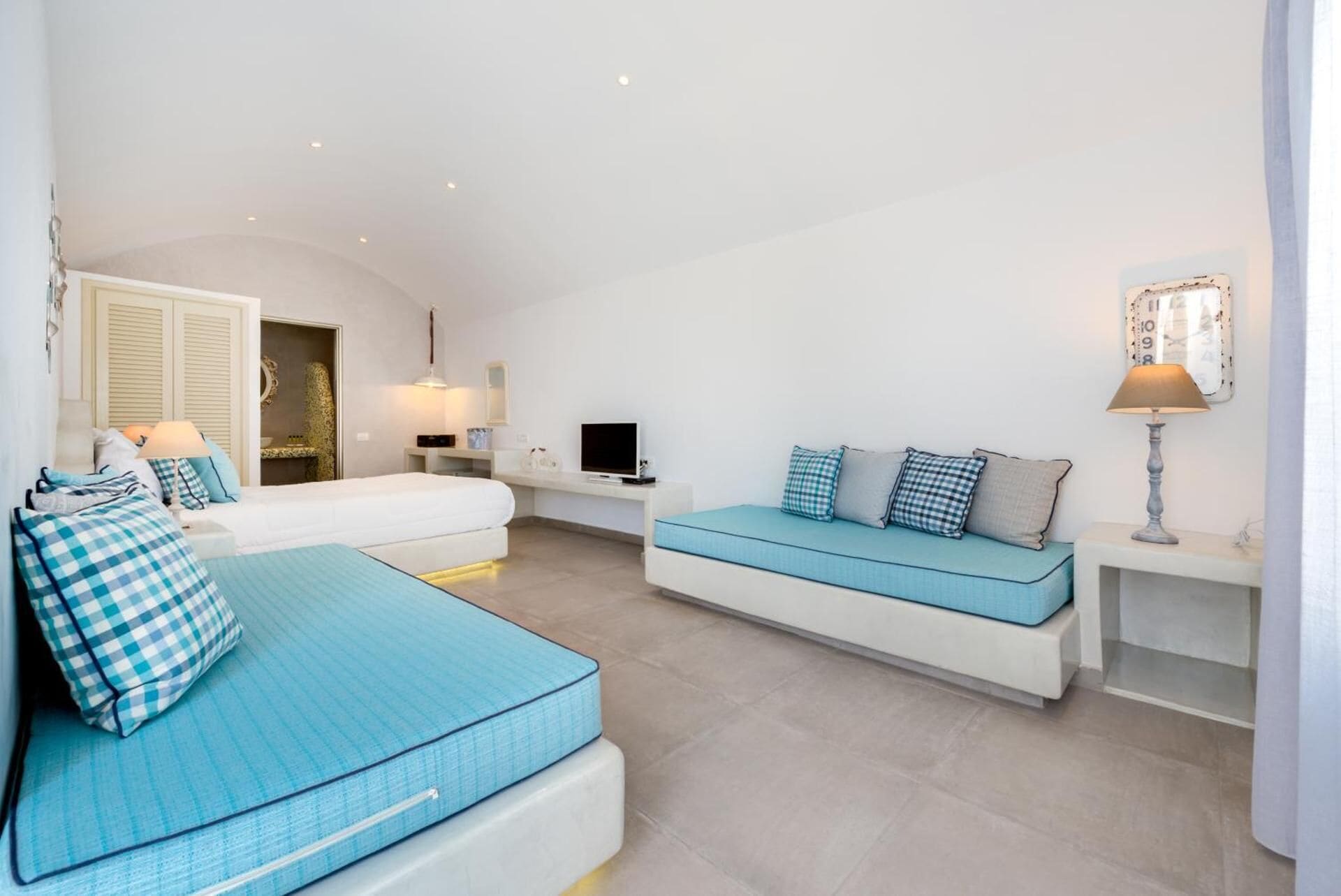 A modern bedroom with a large bed, a sofa, and a TV.