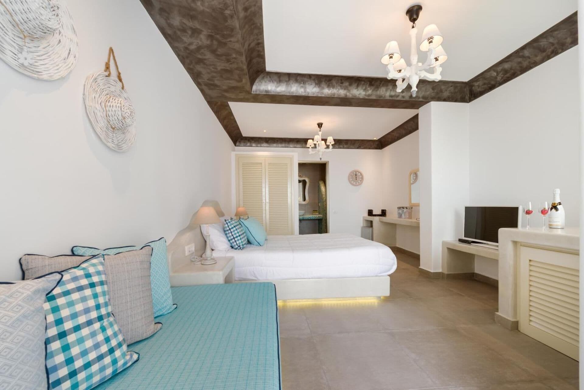 Un dormitorio con cama, mesitas de noche, televisión y minibar.