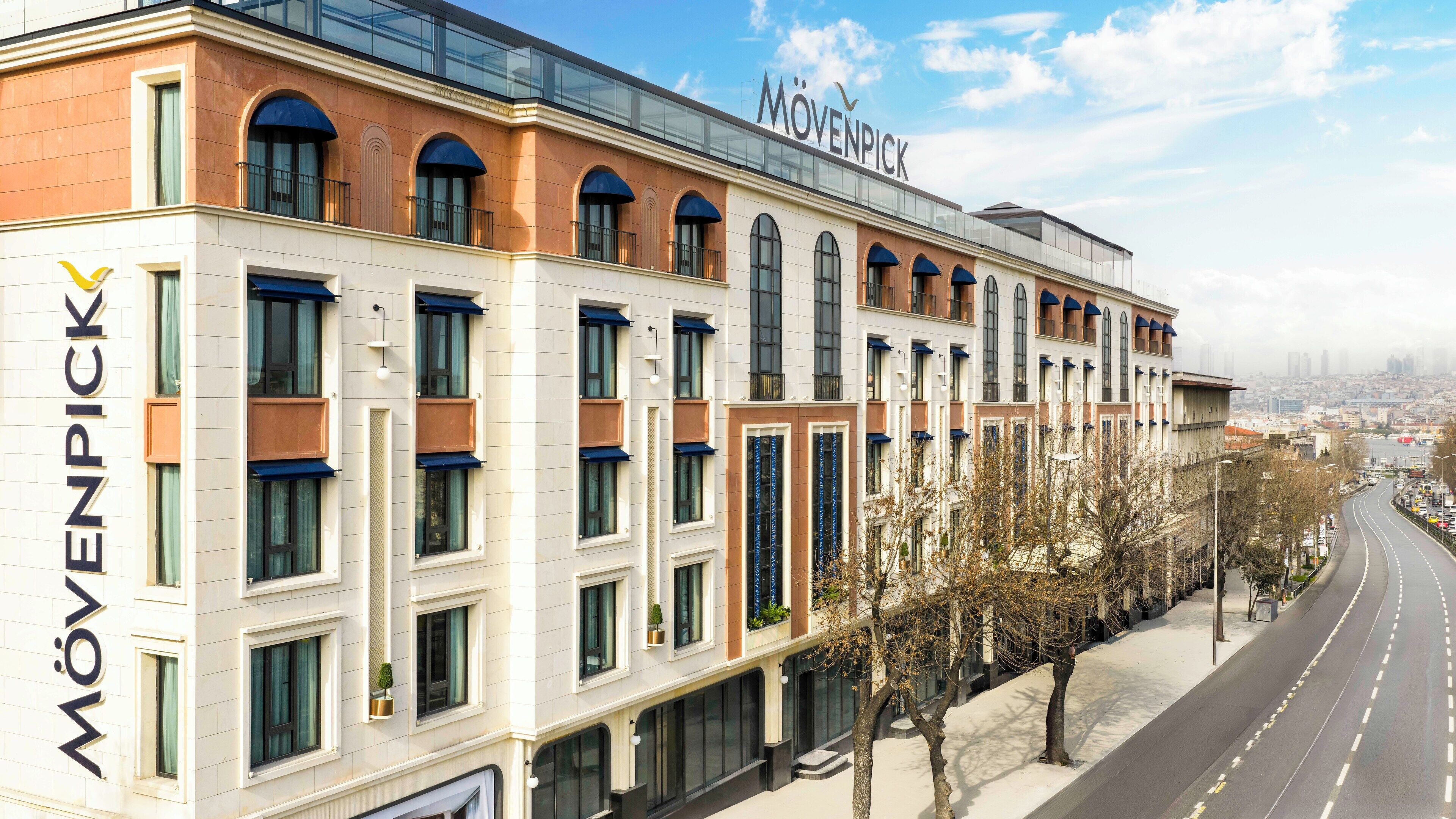 A multi-story hotel with a modern facade, large windows, and a prominent 'Mövenpick' sign.