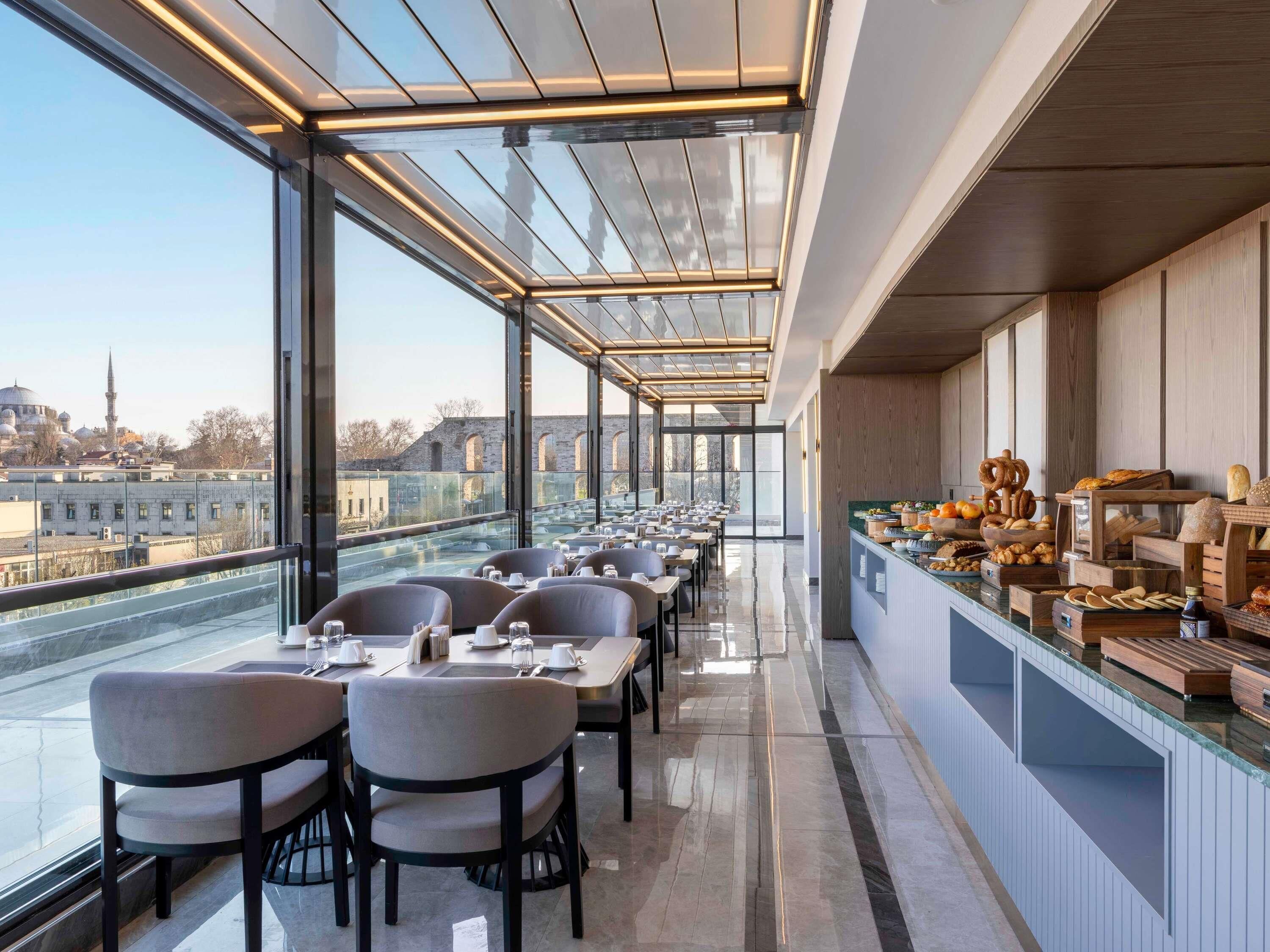 A modern restaurant with a glass ceiling, offering views of a cityscape.