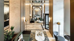 A modern lobby with a central seating area, a high ceiling with a grid-like light fixture, and a view into a dining area. - Mövenpick Istanbul Old Town (Istanbul)