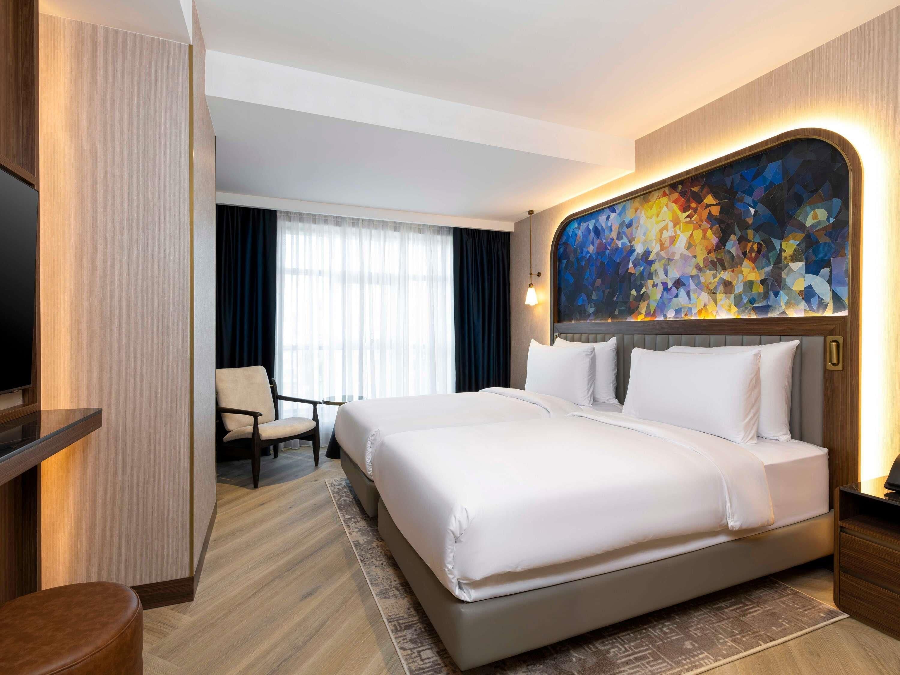 Een hotelkamer met een groot bed, een televisie, een bureau en een stoel.