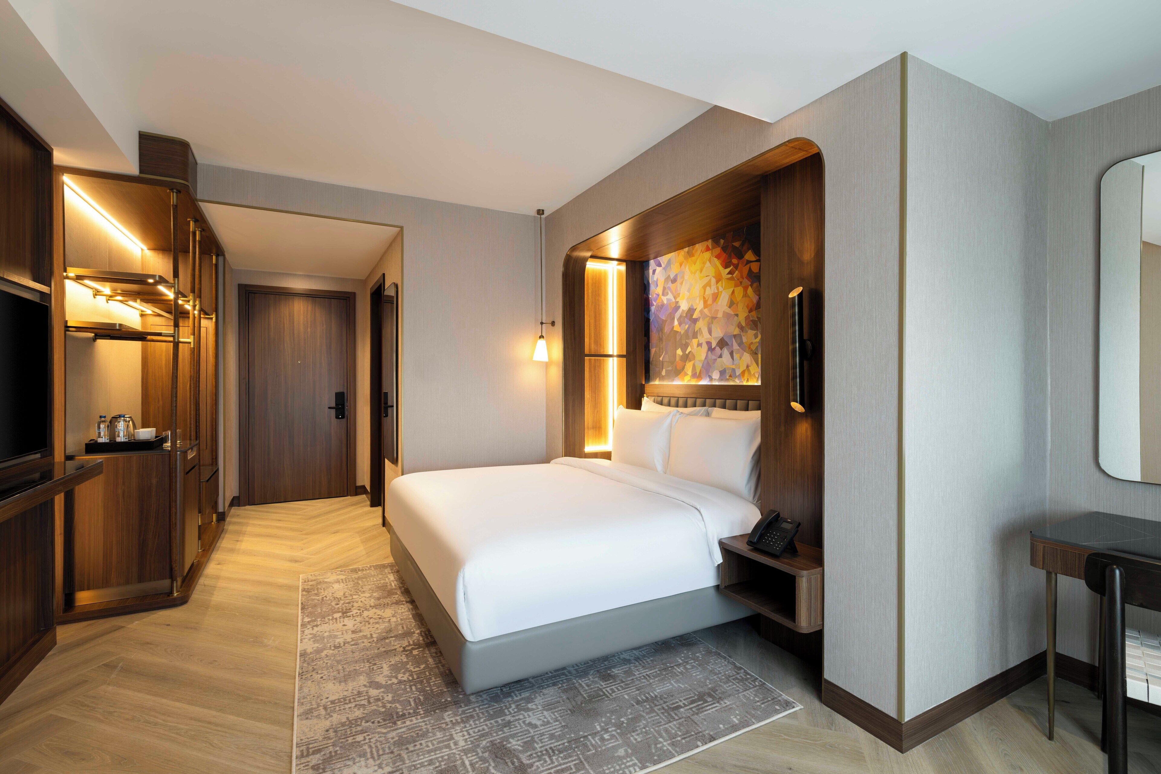 Une chambre d’hôtel moderne équipée d’un grand lit, d’un bureau, d’une télévision et d’une salle de bain.
