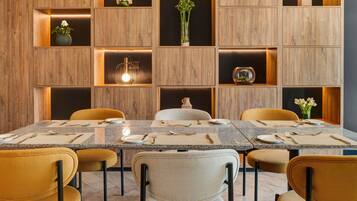 A modern dining area with a rectangular table, six chairs, and built-in wooden shelves with decorative items.