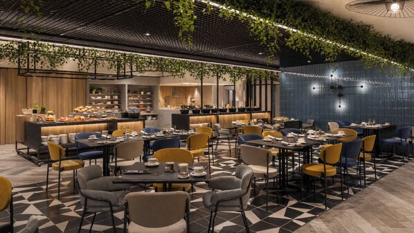 A modern restaurant with a bar area, multiple dining tables, and chairs. - Novotel Madinah (Madinah)