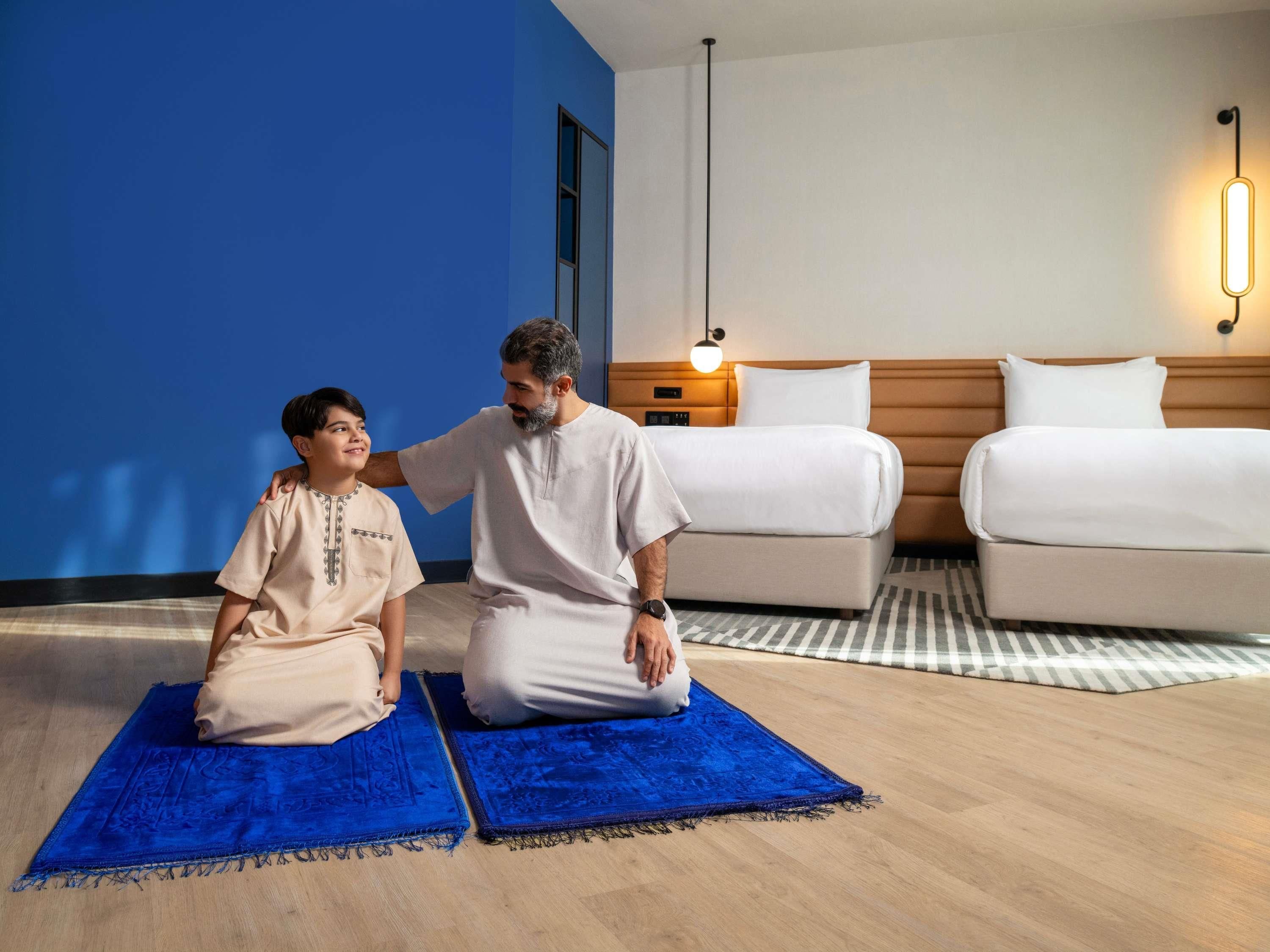 Een hotelkamer met een bed, een nachtkastje en een blauw tapijt.