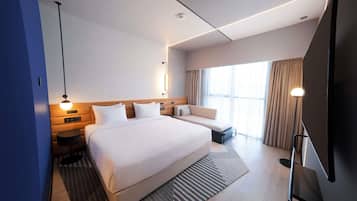 A modern hotel room with a large bed, bedside tables, a TV, and a large window with curtains.