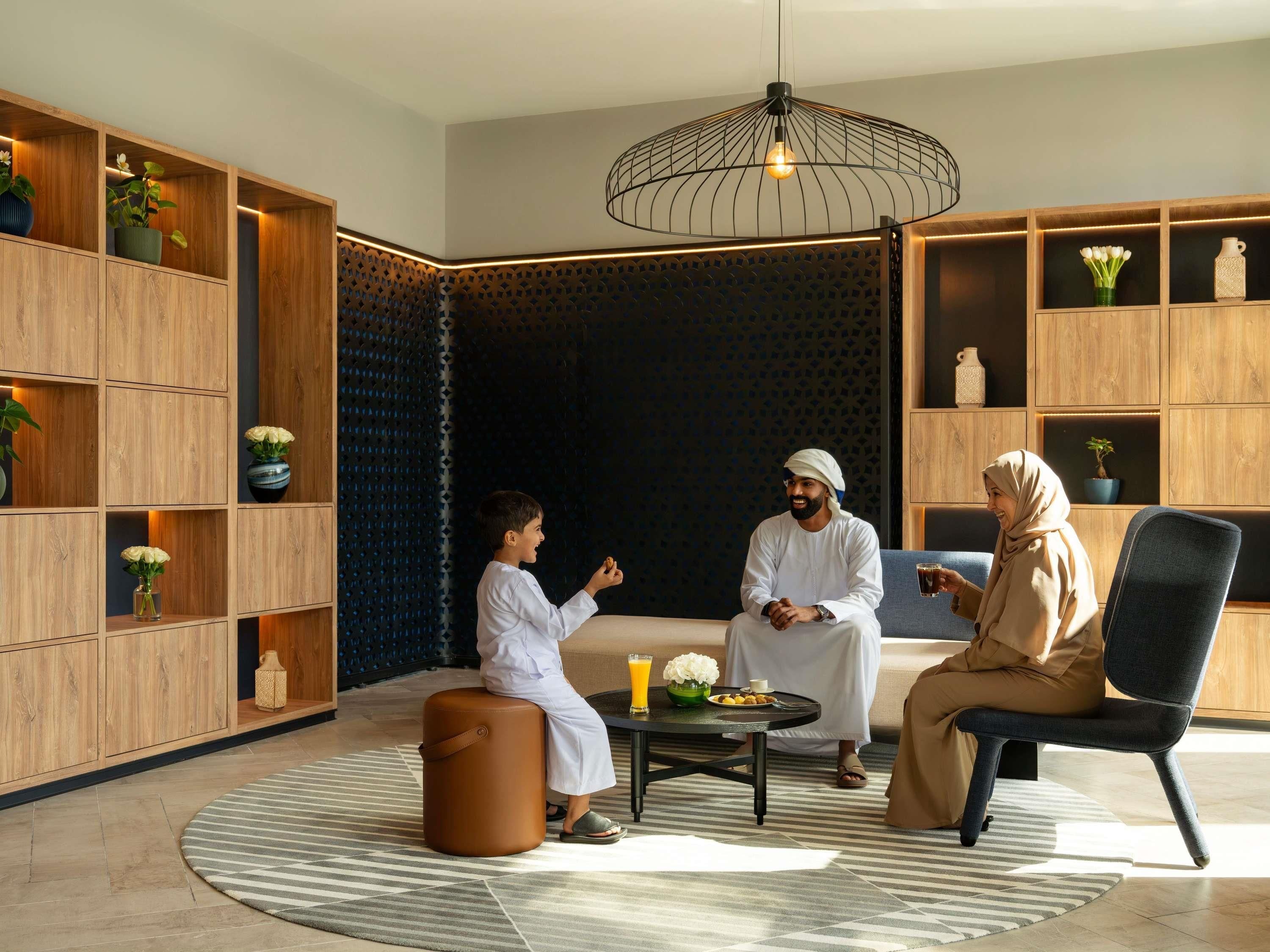 Un intérieur moderne avec des étagères en bois, une table basse ronde et un luminaire suspendu.