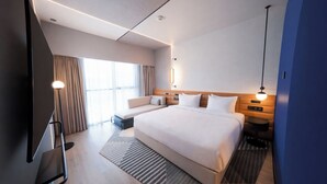 A modern hotel room with a large bed, a flat-screen TV, a seating area, and a large window. - Novotel Madinah (Madinah)